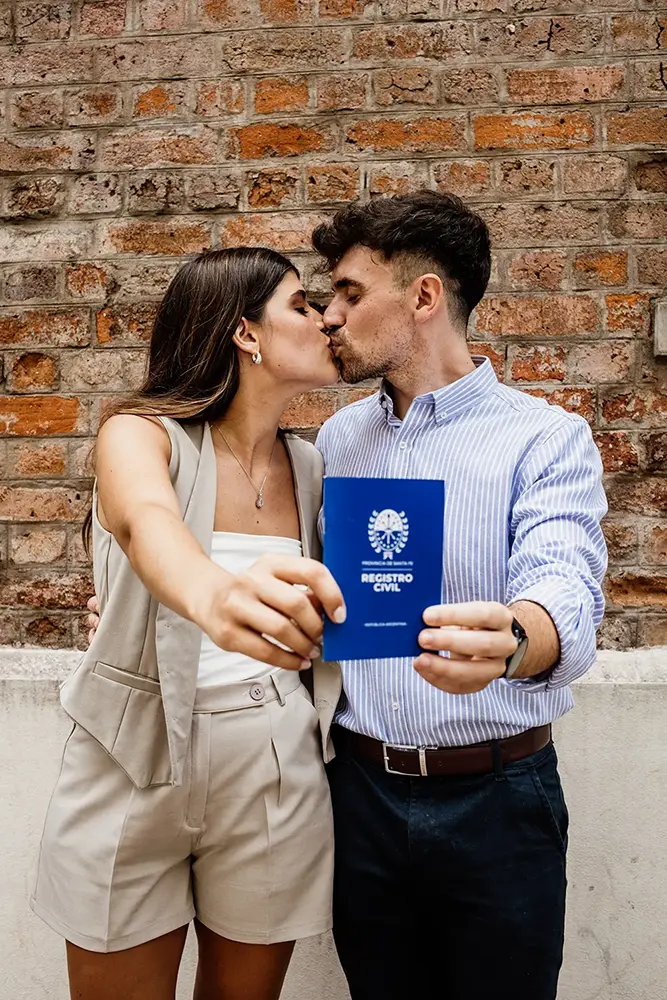 Beso de novios con libreta de casamiento en la mano