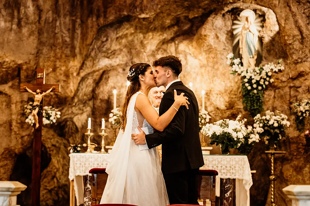 Beso de novios en el final de la ceremonia en la gruta de la iglesia Lourdes