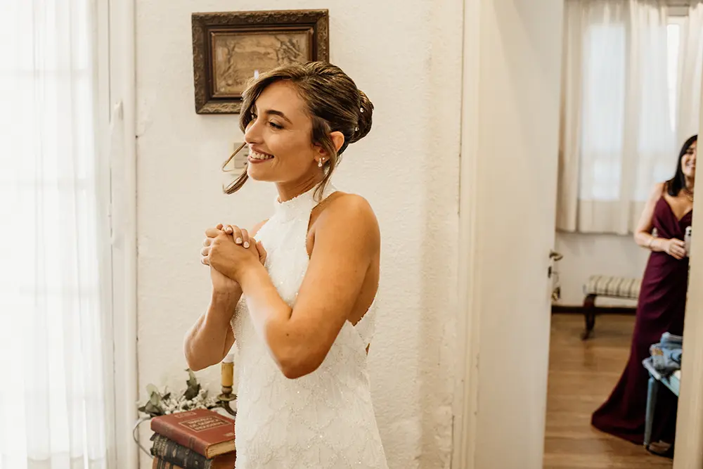 Novia feliz sale de la habitación vestida de blanco