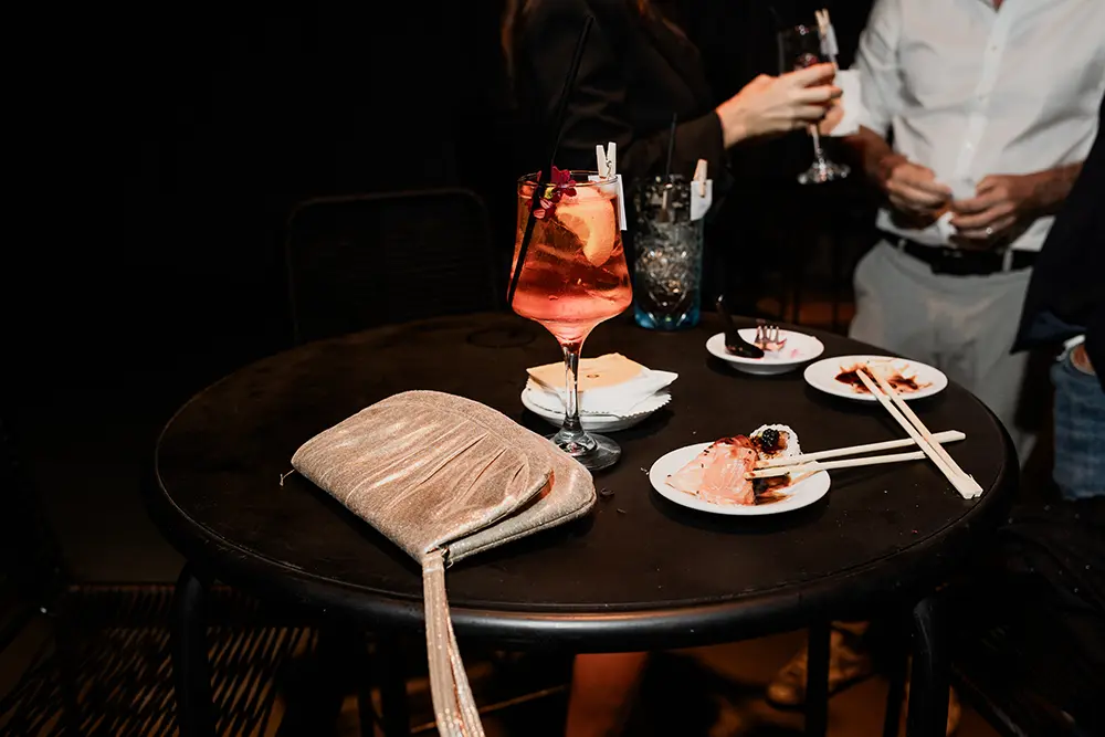 Mesa con trago decorado, sushi y cartera de dama
